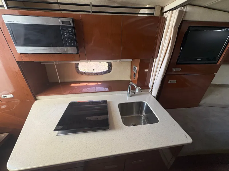 Slide: The Image of The 2010 Sea Ray Sundancer 310 galley features a sink, stove, and microwave. - 32
