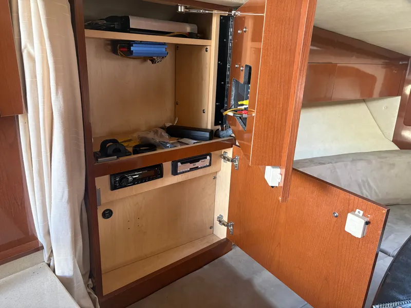 Slide: The Image of An open cabinet inside a 2010 Sea Ray Sundancer 310 reveals electronics and storage space. - 22
