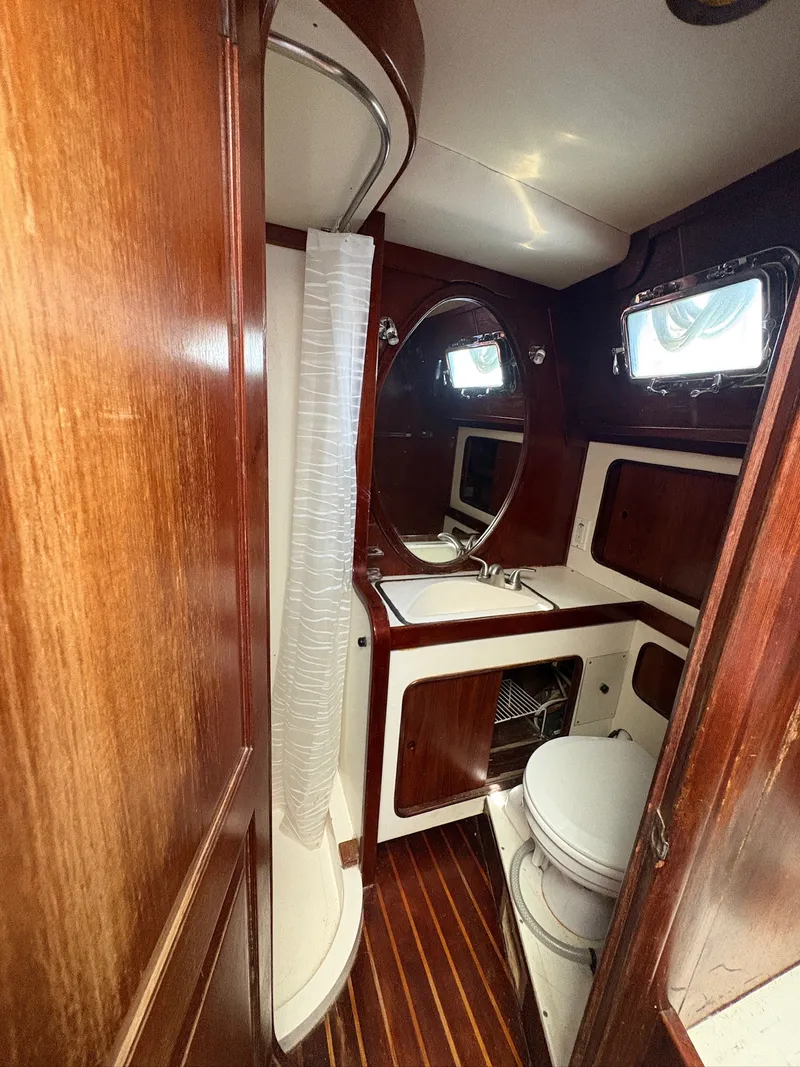 Slide: The Image of The image shows a yacht bathroom with wooden walls, a sink, toilet, and a porthole. - 37