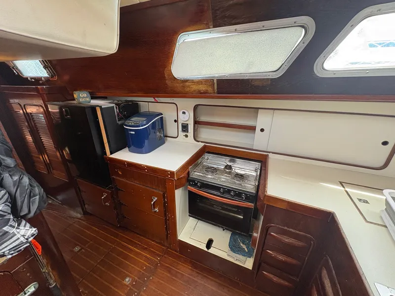 Slide: The Image of The galley of a 1980 Gulfstar 50 CC Ketch with wood paneling, stove, and storage space. - 26