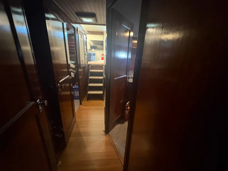 Slide: The Image of A narrow hallway in a boat with wooden walls and doors leads to a staircase. - 28