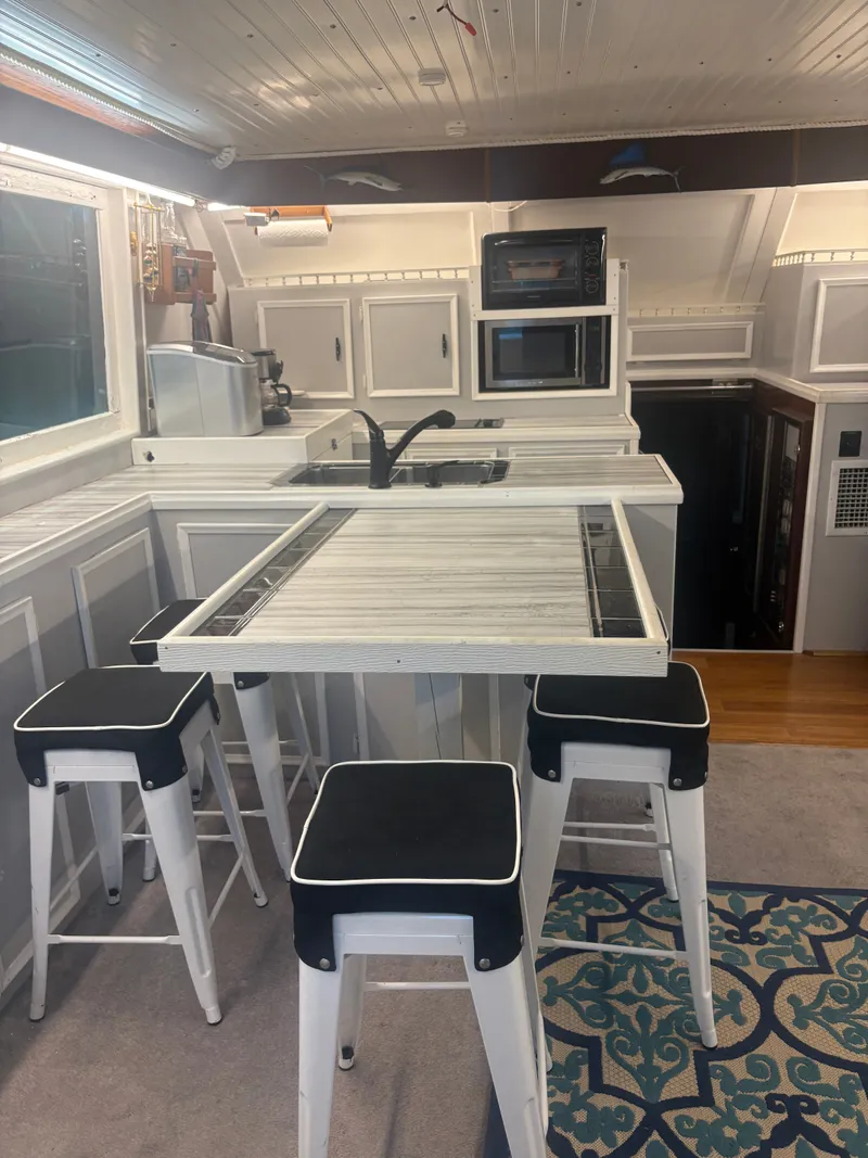 Slide: The Image of Interior of a 1973 Hatteras 53 Convertible with a modern kitchen and bar stools. - 17