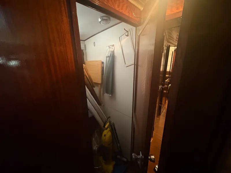 Slide: The Image of A narrow space with wooden doors and cleaning equipment aboard a 1973 Hatteras 53 Convertible. - 43