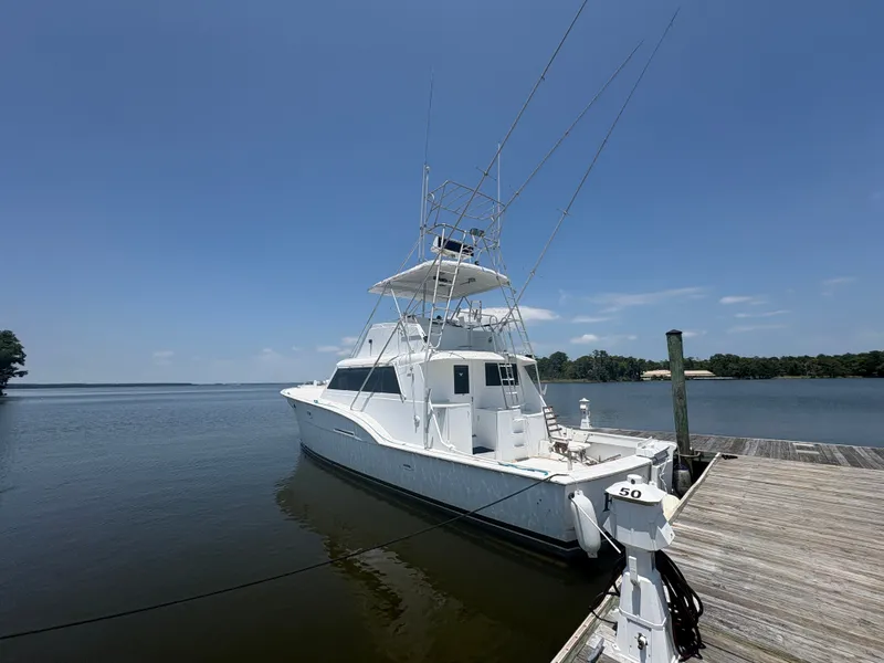 The Image of A 1973 Hatteras 53 Convertible docked at a serene pier under a clear sky. - 1