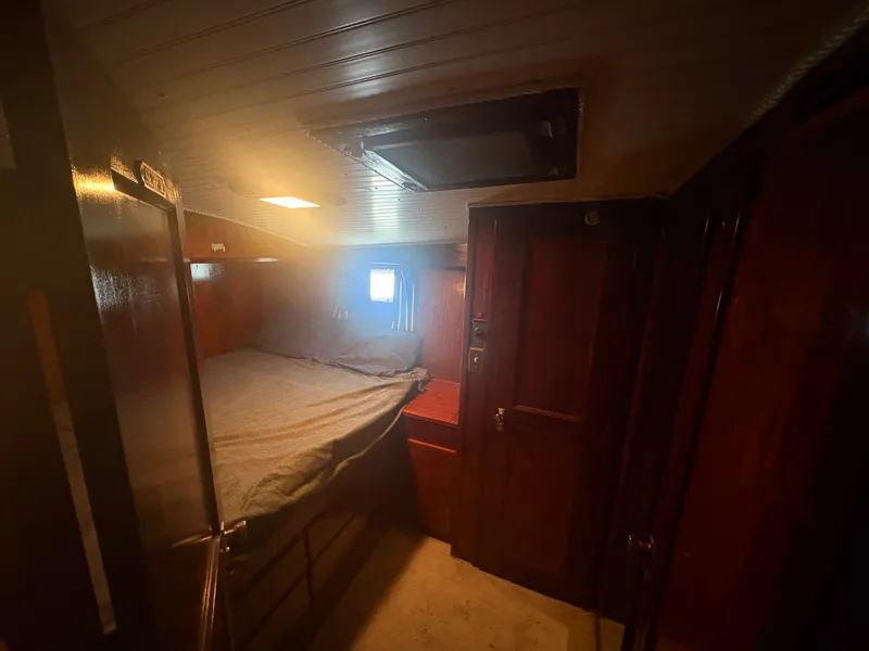 Slide: The Image of A cozy bedroom with wooden walls and a small window aboard a Hatteras 53 Convertible. - 46