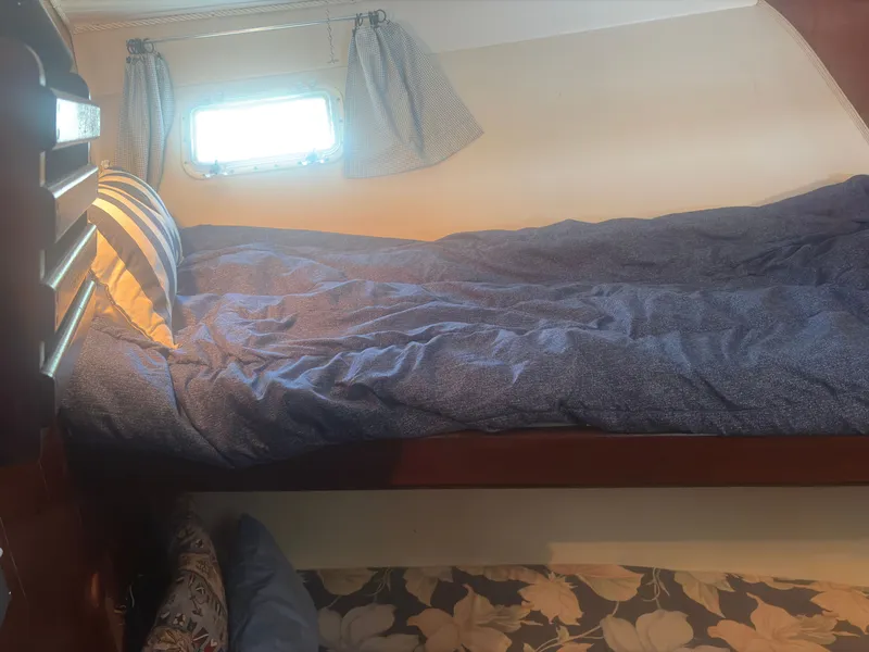 Slide: The Image of A cozy cabin with a single bed, blue bedding, and a small window. - 37