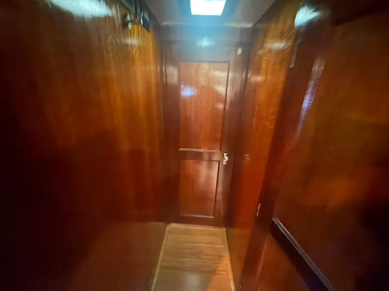 Slide: The Image of A sleek, wood-paneled hallway with a door at the end, illuminated by a skylight. - 41