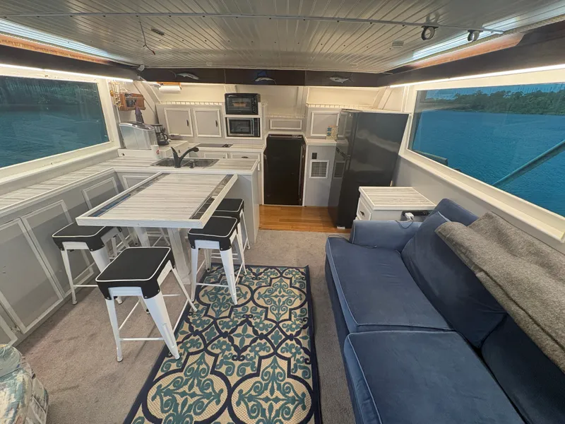 Slide: The Image of Interior of a 1973 Hatteras 53 Convertible with kitchen, dining table, and blue couch. - 15
