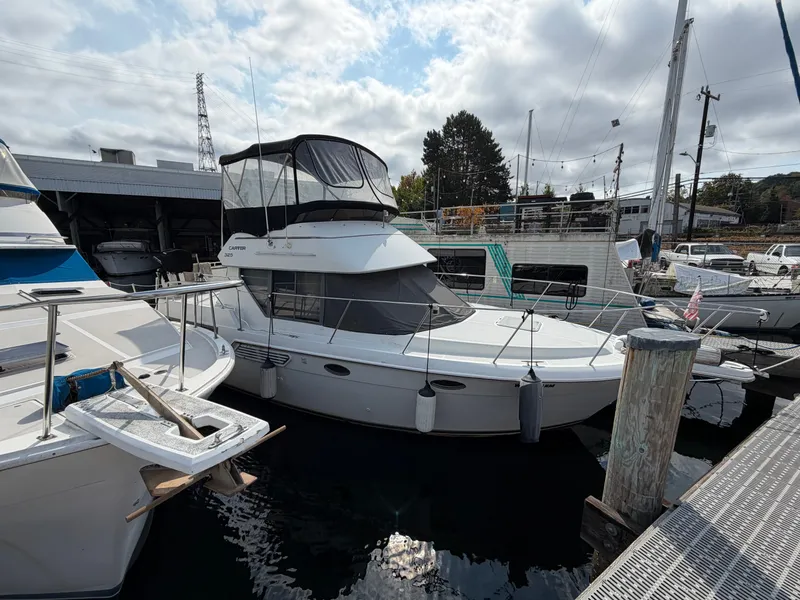 The Image of A 1996 Carver 325 Aft Cabin Motor Yacht docked in a marina. It features a spacious deck and covered flybridge. - 3