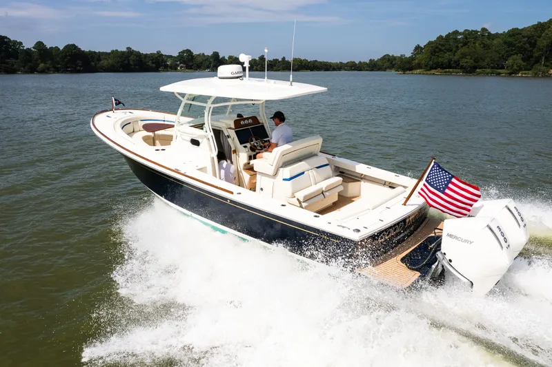Slide: The Image of 2024 Hunt Yachts 32CC cruising on a lake with American flag and twin Mercury engines. - 5