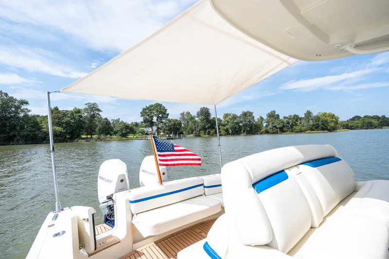 Slide: The Image of 2024 Hunt Yachts 32CC boat with American flag, shaded seating, and scenic water view. - 40