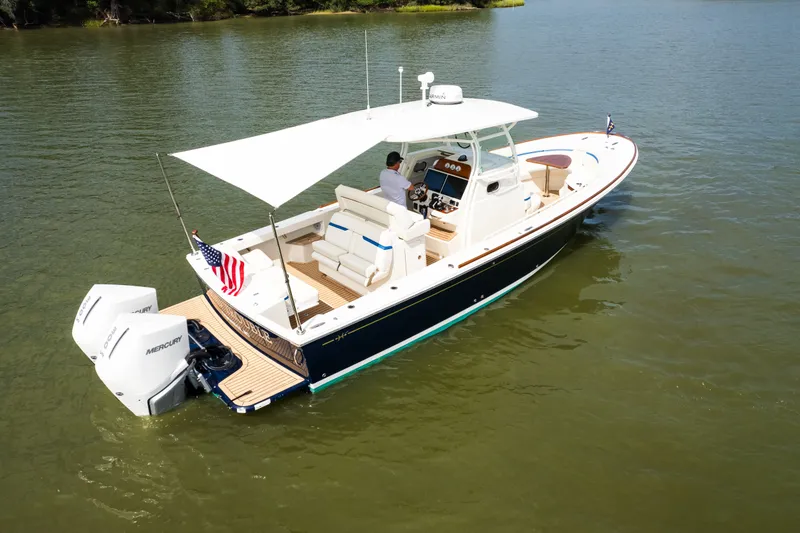 Slide: The Image of 2024 Hunt Yachts 32CC boat on calm water, featuring dual Mercury engines and a shaded deck. - 7