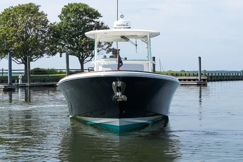 Slide: The Image of 2024 Hunt Yachts 32CC boat on calm water near a dock, with trees in the background. - 2