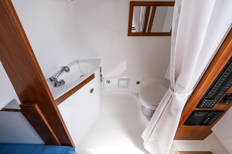Slide: The Image of 2024 Hunt Yachts 32CC bathroom with sink, toilet, and wooden accents. - 33