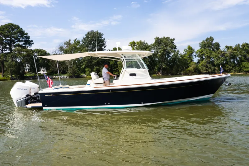 Slide: The Image of 2024 Hunt Yachts 32CC cruising on a calm river with lush green trees in the background. - 6