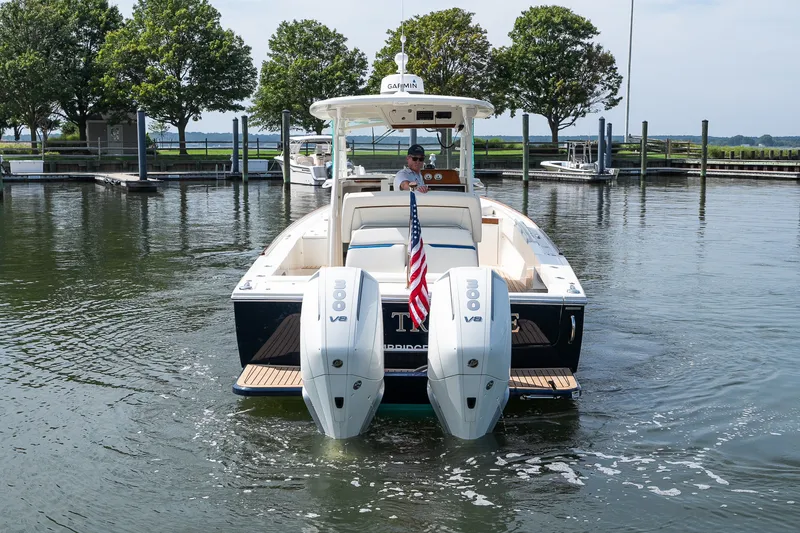 Slide: The Image of 2024 Hunt Yachts 32CC boat with dual engines, navigating a marina. - 12