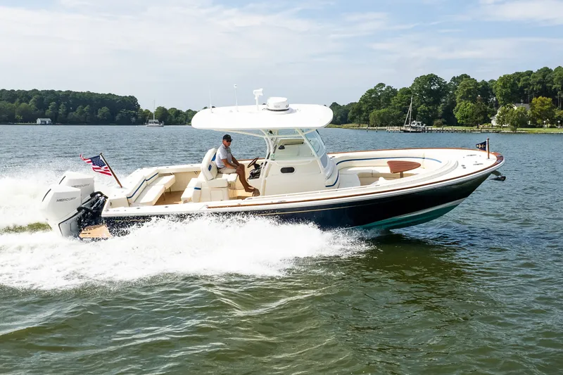 Slide: The Image of 2024 Hunt Yachts 32CC cruising on a lake with lush green shoreline. - 4