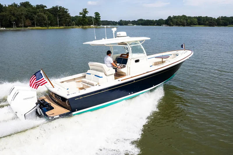 Slide: The Image of 2024 Hunt Yachts 32CC cruising on a serene lake with American flag. - 1