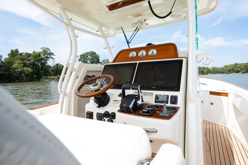 Slide: The Image of 2024 Hunt Yachts 32CC helm with advanced navigation systems and luxurious design on a serene waterway. - 26