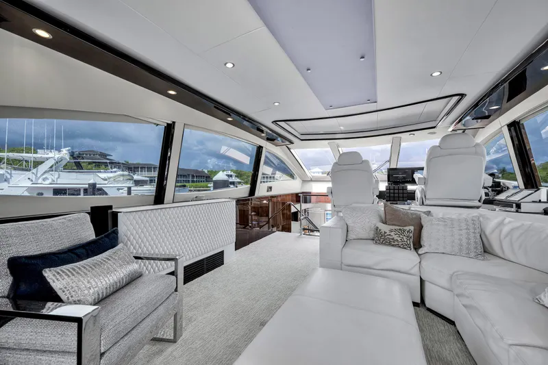 Slide: The Image of Innenraum einer luxuriösen Yacht mit weißen Ledersofas und großen Fenstern, die einen Hafen überblicken. - 5