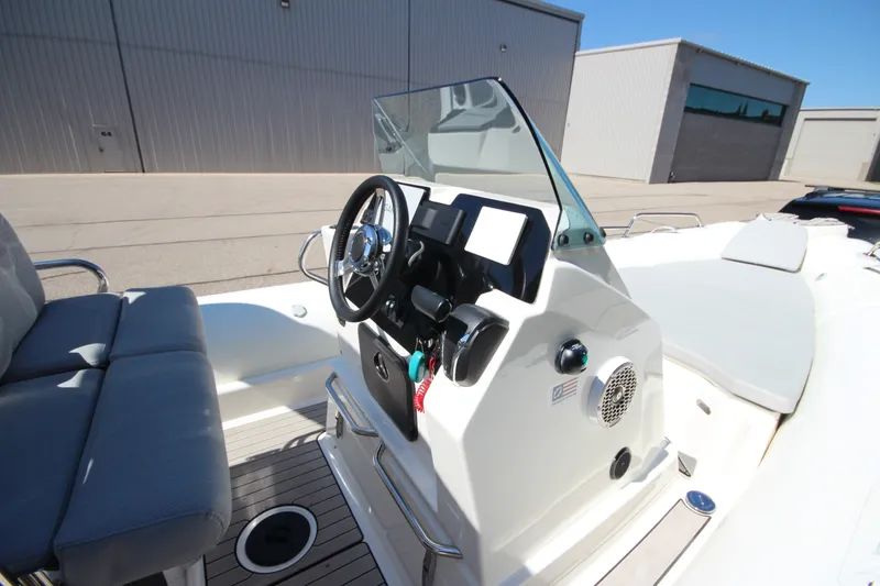 Slide: The Image of 2023 Zodiac Medline 7.5 boat cockpit with steering wheel and seating, docked outdoors. - 21