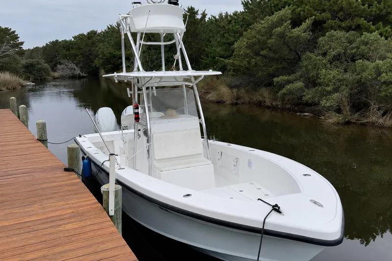 The Image of 2021 Ocean Master 27 boat docked on a calm waterway, surrounded by lush greenery. - 0