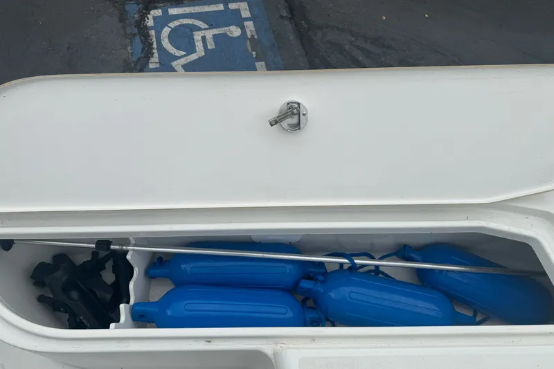 Slide: The Image of Open storage compartment on 2012 Ranger 220 Bahia boat with blue fenders inside. - 15