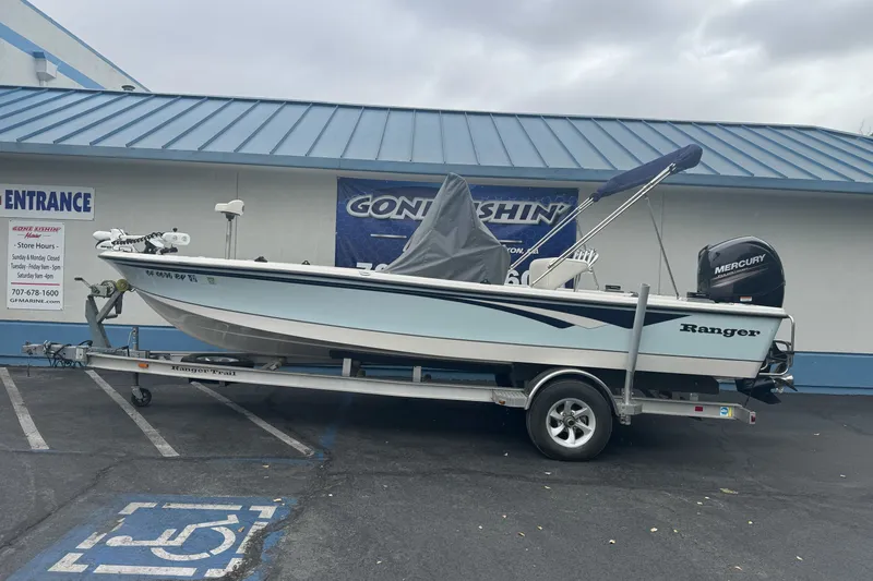 The Image of 2012 Ranger 220 Bahia boat on trailer, parked outside a marine store. - 1