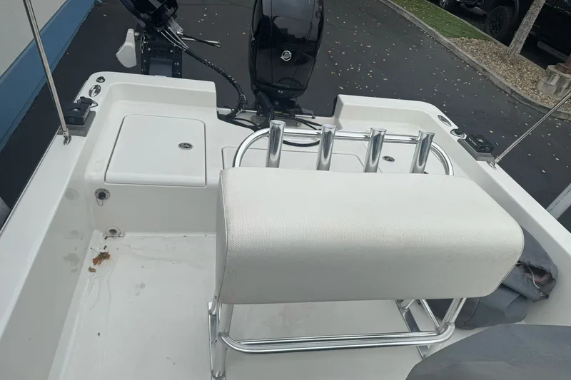 Slide: The Image of 2012 Ranger 220 Bahia boat interior with seating and motor, parked on pavement. - 10
