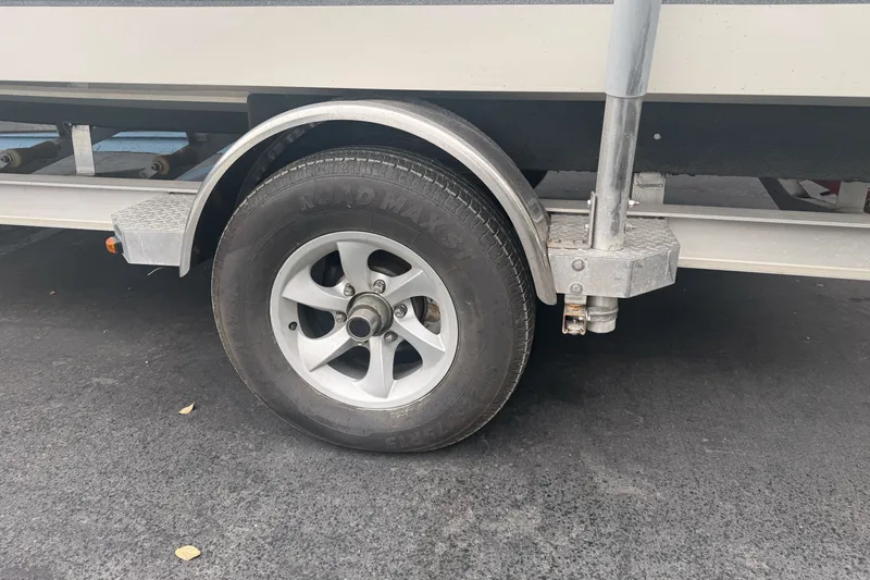 Slide: The Image of Trailer wheel of a 2012 Ranger 220 Bahia boat on asphalt surface. - 8
