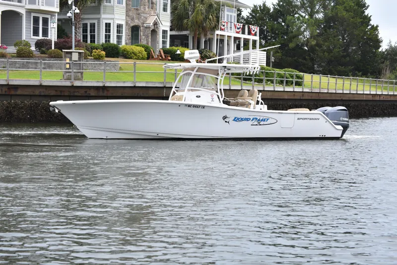 Slide: The Image of 2017 Sportsman Open 312 Center Console boat cruising near waterfront homes. - 2