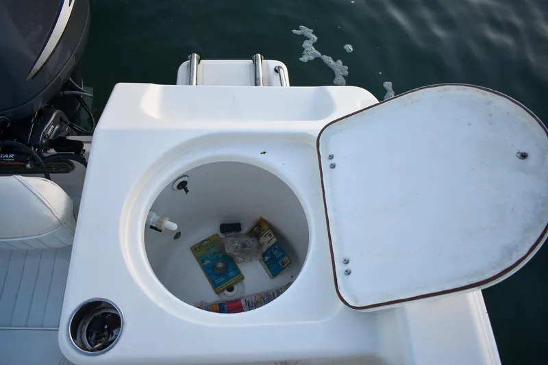 Slide: The Image of Open storage compartment on 2007 Tidewater 216 CC Adventure boat, showing various items inside. - 13