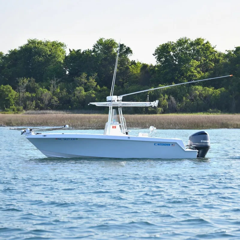The Image of 2014 Contender 23 Open boat on water, surrounded by lush greenery. - 0