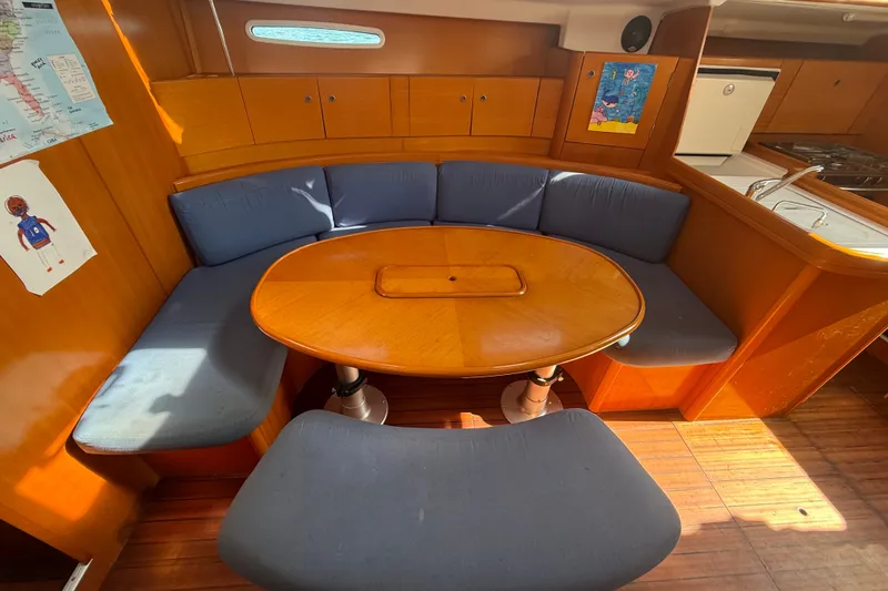 Slide: The Image of Interior of 2006 Beneteau First 44.7 yacht with wooden dining area and blue cushions. - 23