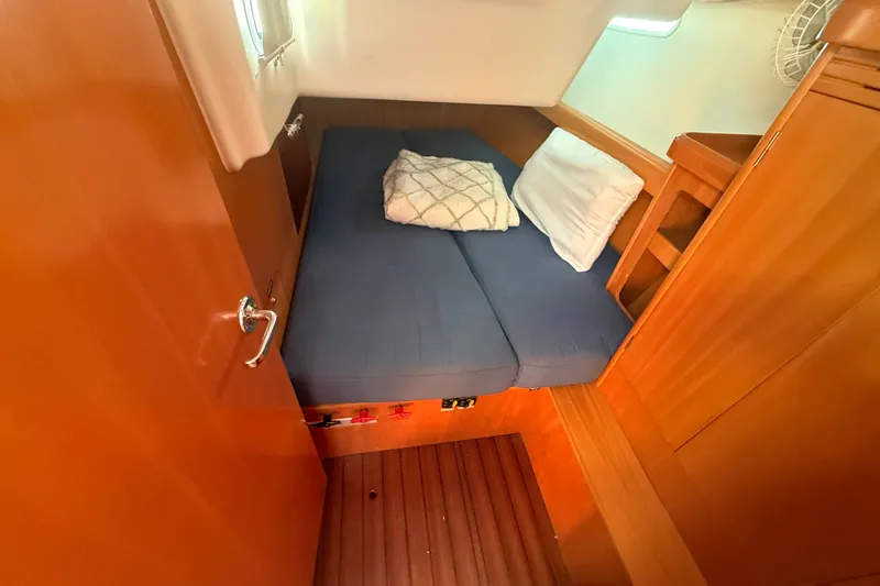 Slide: The Image of Cozy cabin interior of 2006 Beneteau First 44.7 sailboat with blue bedding and wooden finish. - 28