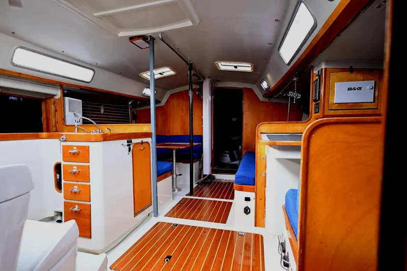 Slide: The Image of Interior of a 1992 Santa Cruz 52 yacht, featuring wood finishes and blue seating. - 13