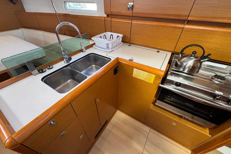 Slide: The Image of 2018 Jeanneau Sun Odyssey 389 yacht kitchen with sink, stove, and wooden cabinetry. - 41