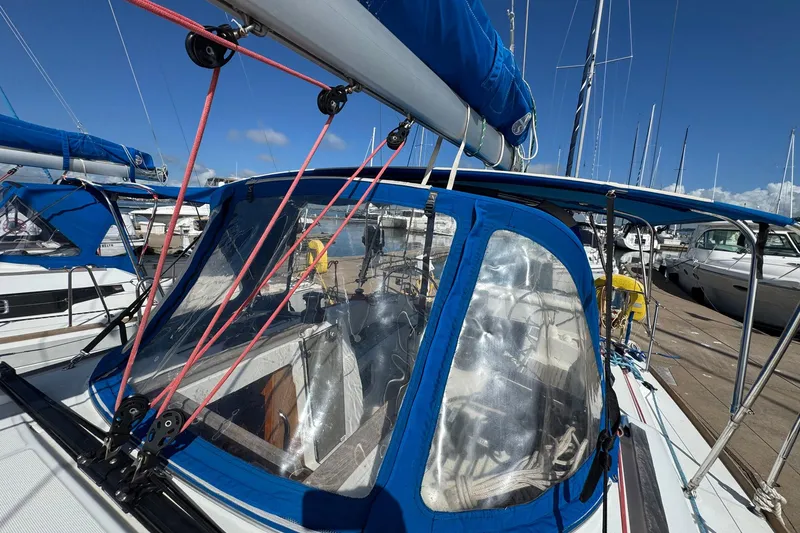 Slide: The Image of 2018 Jeanneau Sun Odyssey 389 sailboat docked, featuring blue canopy and rigging. - 18