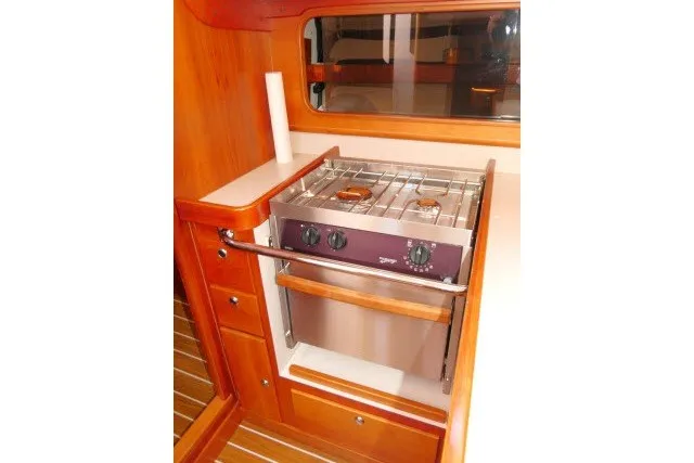 Slide: The Image of 2004 J Boats J/109 yacht interior with a compact kitchen stove and wooden cabinetry. - 19