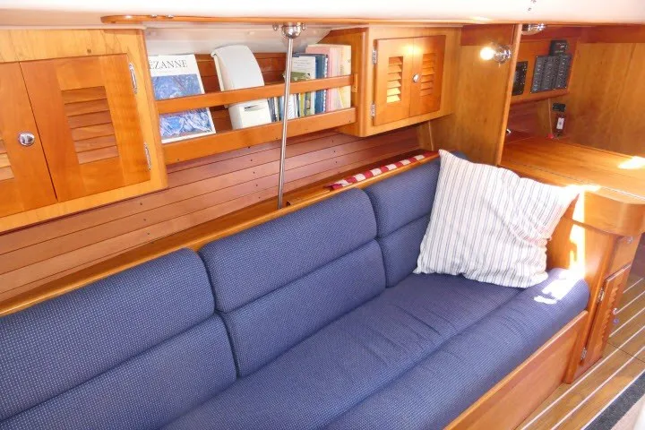Slide: The Image of Interior of 2004 J Boats J/109 sailboat with blue cushioned seating and wooden cabinetry. - 16