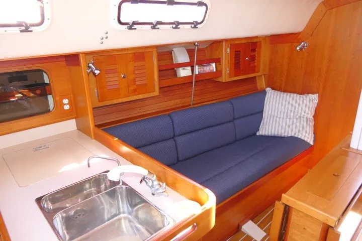 Slide: The Image of Interior of 2004 J Boats J/109 sailboat with blue cushioned seating and wooden cabinetry. - 5