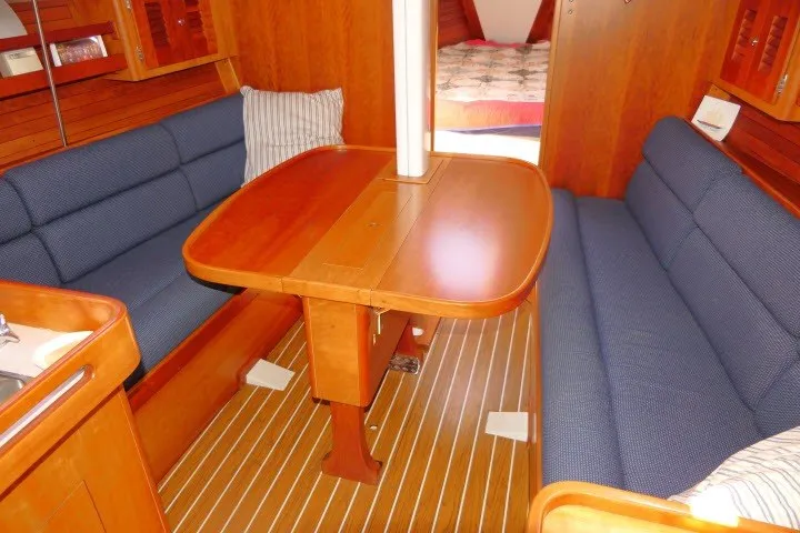Slide: The Image of Interior of 2004 J Boats J/109 sailboat with wooden table and blue seating. - 7