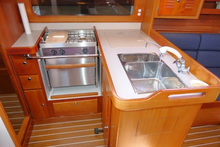 Slide: The Image of 2004 J Boats J/109 yacht interior kitchen with stove, sink, and wooden cabinetry. - 18