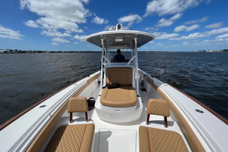 Slide: The Image of 2020 Valhalla 33 boat on open water, featuring tan quilted seating and clear blue skies. - 6