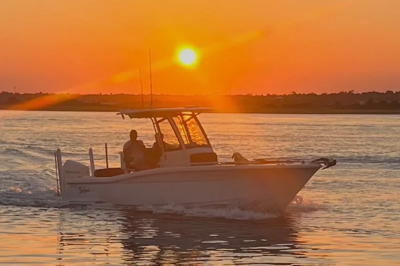 Slide: The Image of 2024 Scout 240 XSF boat cruising at sunset on calm waters. - 0