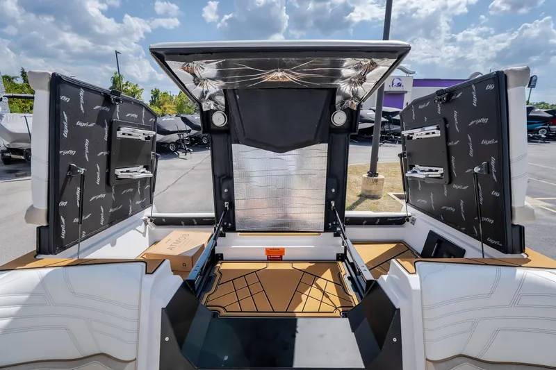 Slide: The Image of 2027 Tigé Ultré 23ZX boat interior with open storage compartments under a sunny sky. - 60