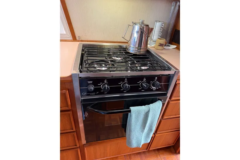 Slide: The Image of 1990 Cruise-A-Home Corsair kitchen with stove, kettle, and teal towel. - 58