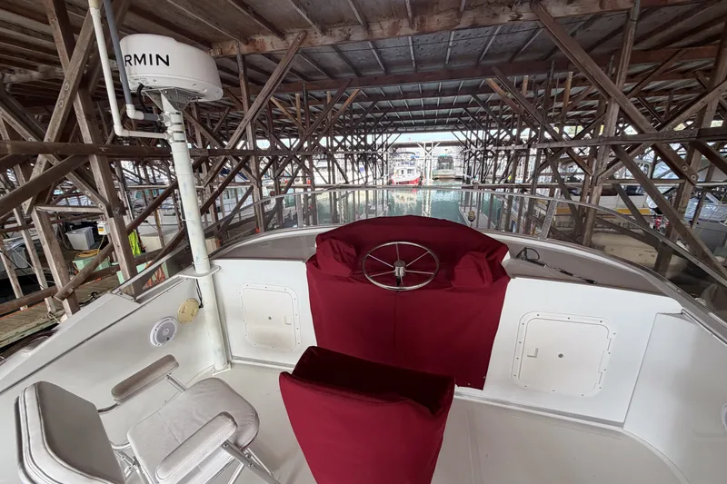 Slide: The Image of 1990 Cruise-A-Home Corsair boat helm with red covers in a wooden dock. - 13