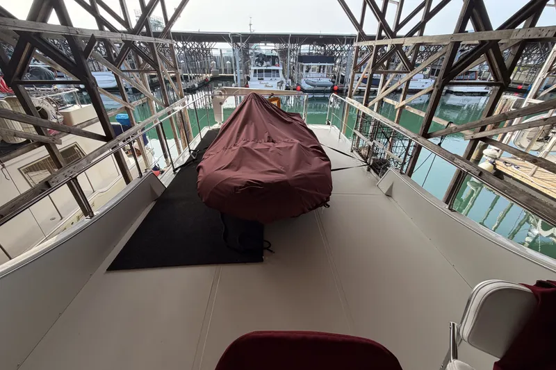Slide: The Image of 1990 Cruise-A-Home Corsair boat deck with covered equipment, docked in marina. - 17