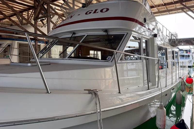 Slide: The Image of 1990 Cruise-A-Home Corsair boat docked in a marina, featuring sleek design and sturdy railings. - 76
